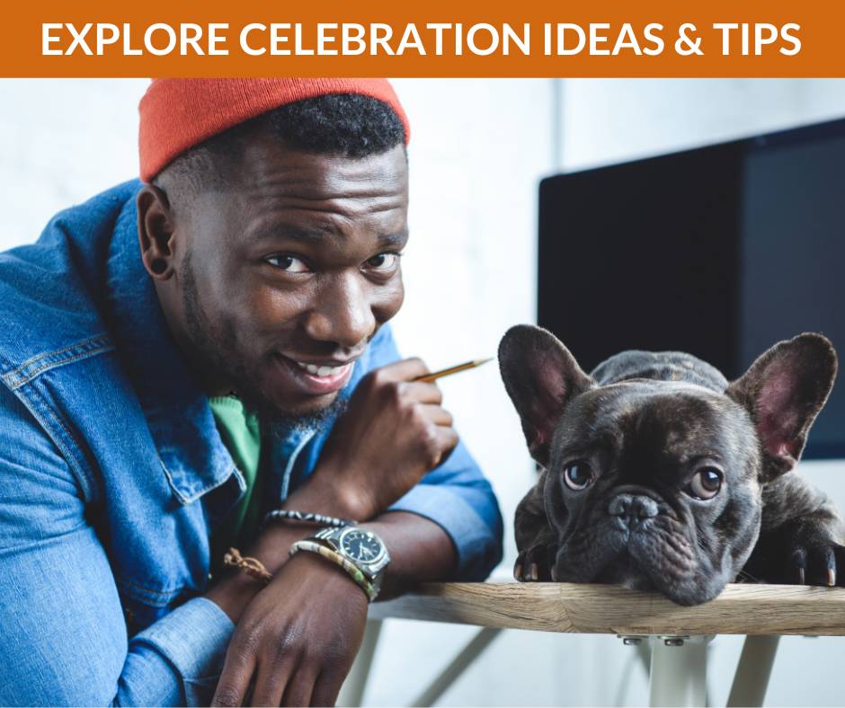 Young creative professional smiles at the camera while a small dog sits next to him.