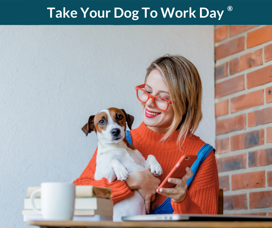 A smiling woman holds a dog and a phone.